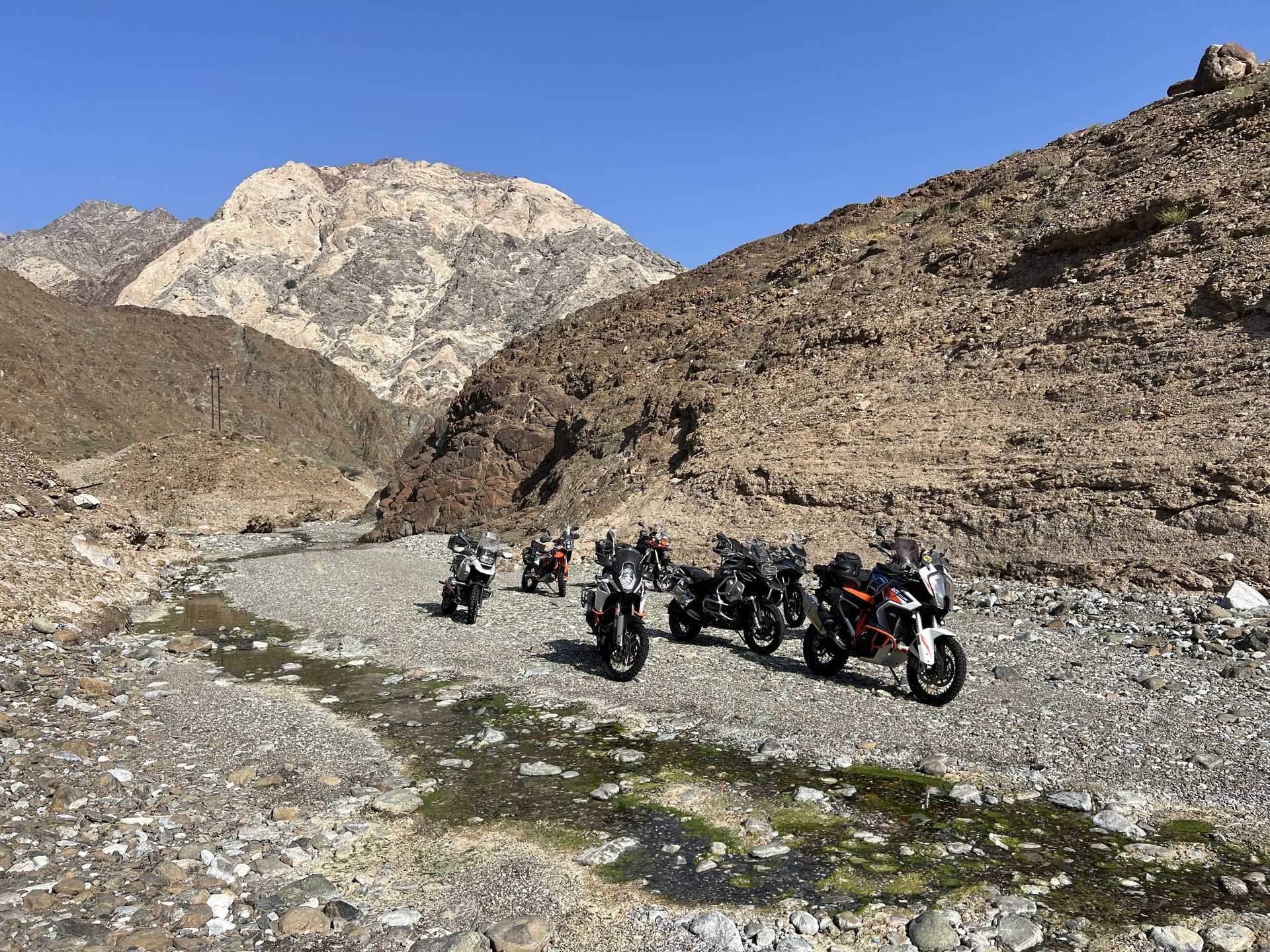 Adventure bikes lined up in a Hajar wadi