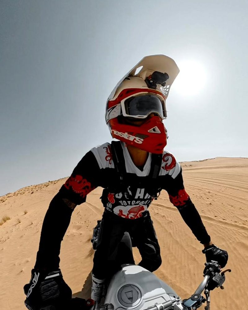 John standing on the pegs of his Ducati DesertX in the dunes